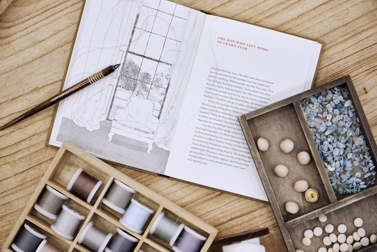 Craft supplies and a book lay on a wooden surface.