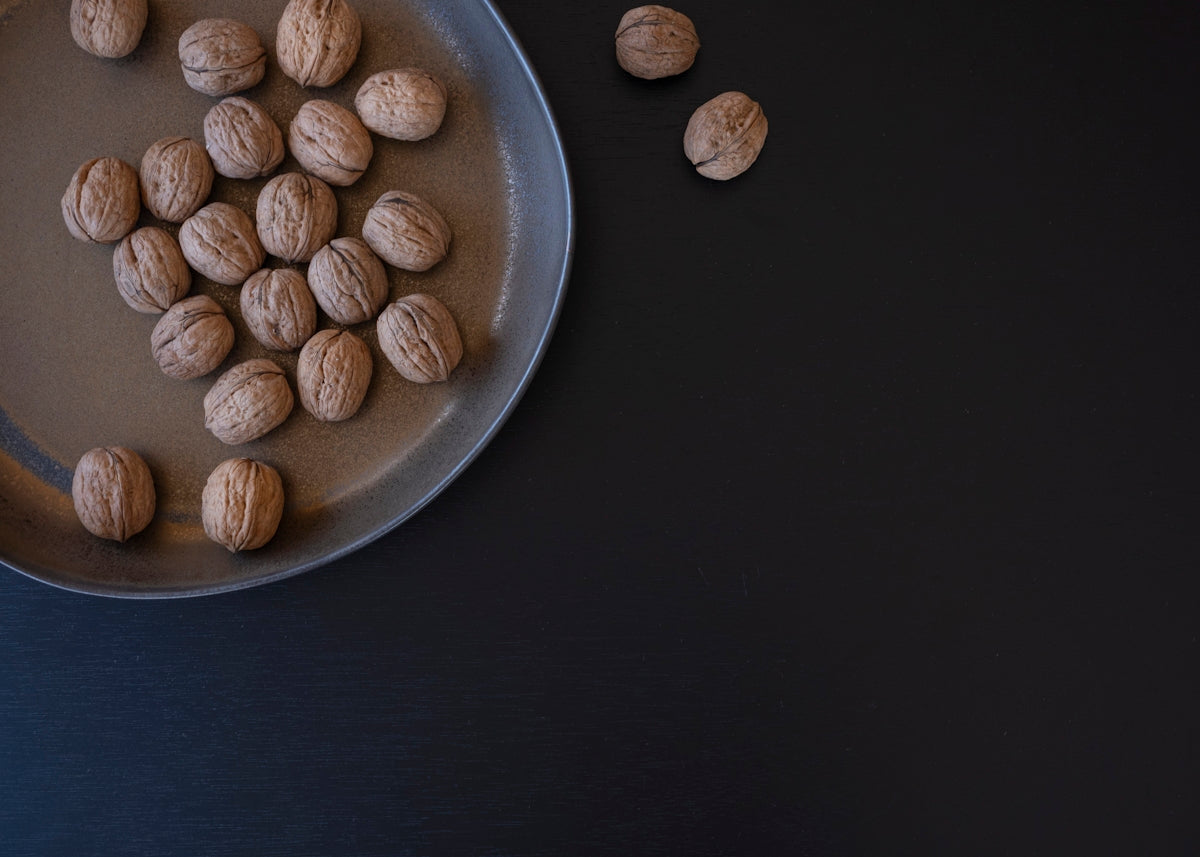 Walnuts scattered on a dark surface and in a bowl.