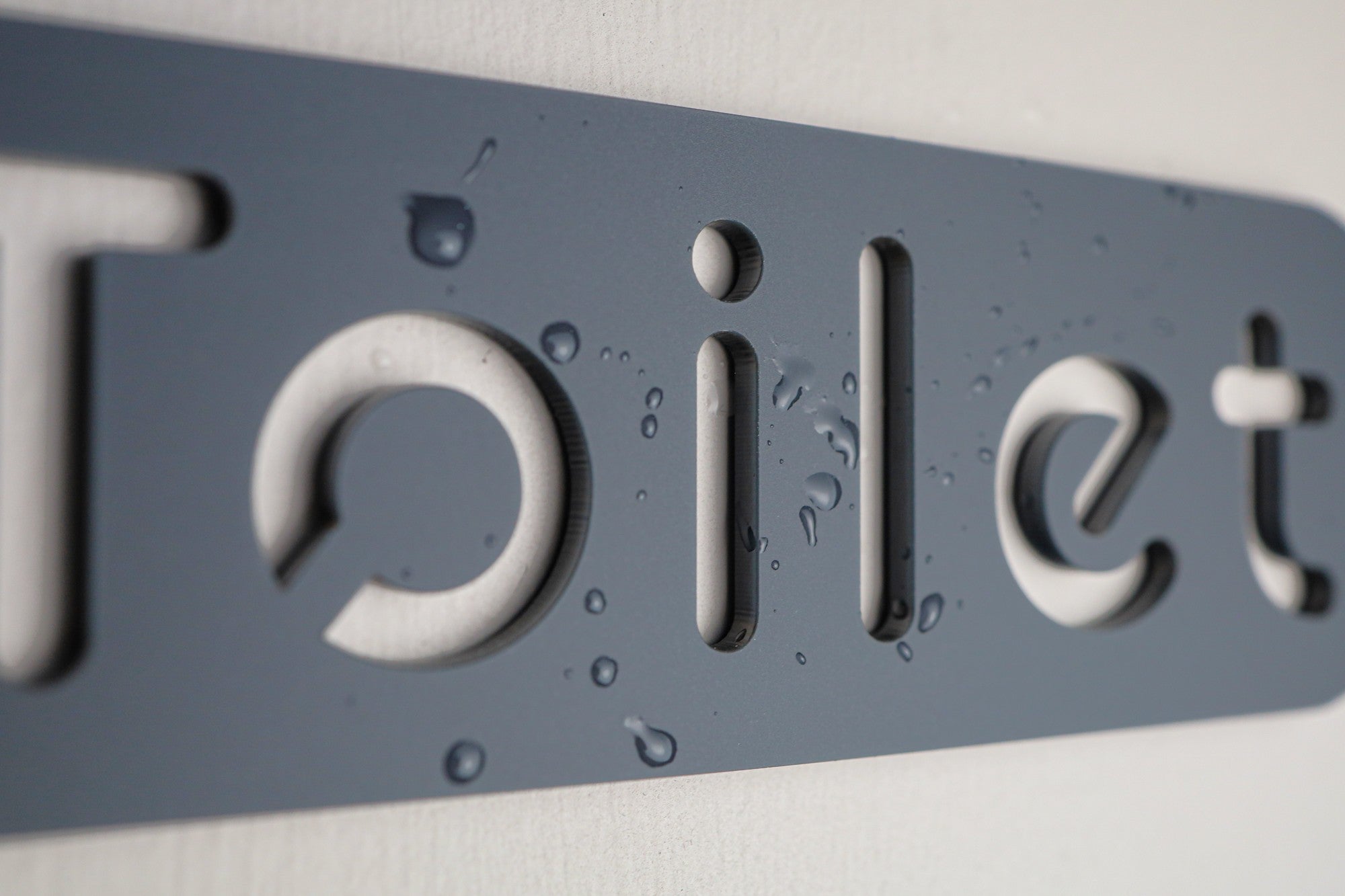 Minimalist grey restroom sign with stone texture and modern typography.