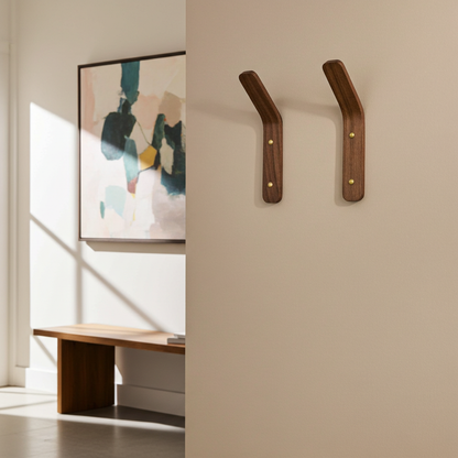 Two wooden wall hooks on a beige wall with abstract art and a bench in the background.